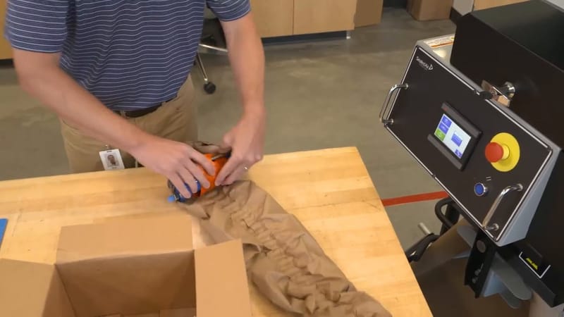 Packer wrapping a part in paper cushioning from a ProPad machine