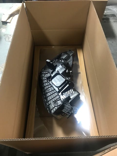 An automotive part suspended in a Korrvu retention pack inside an open carton