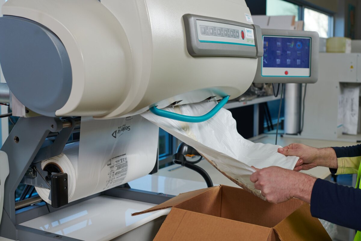 SpeedyPacker film roll feeding the machine as a packer pulls a finished foam bag